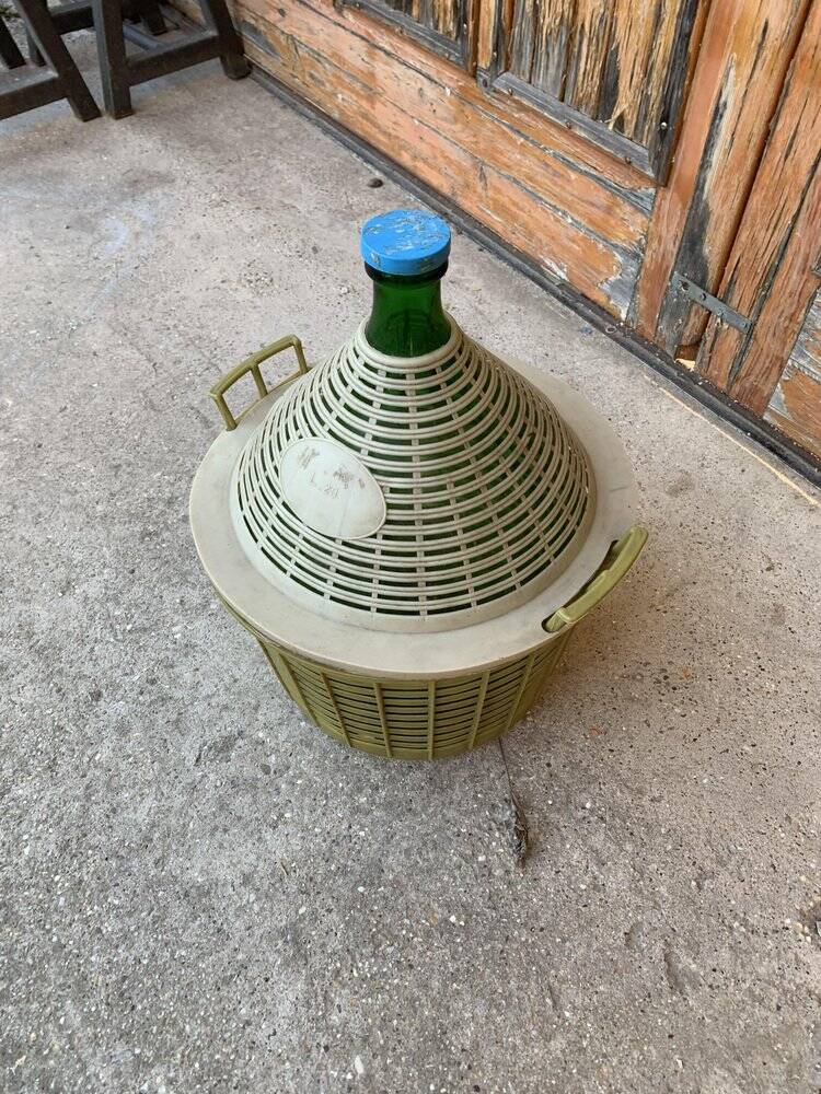 Large green glass lady-Jeanne in a khaki plastic basket, mid-century style.