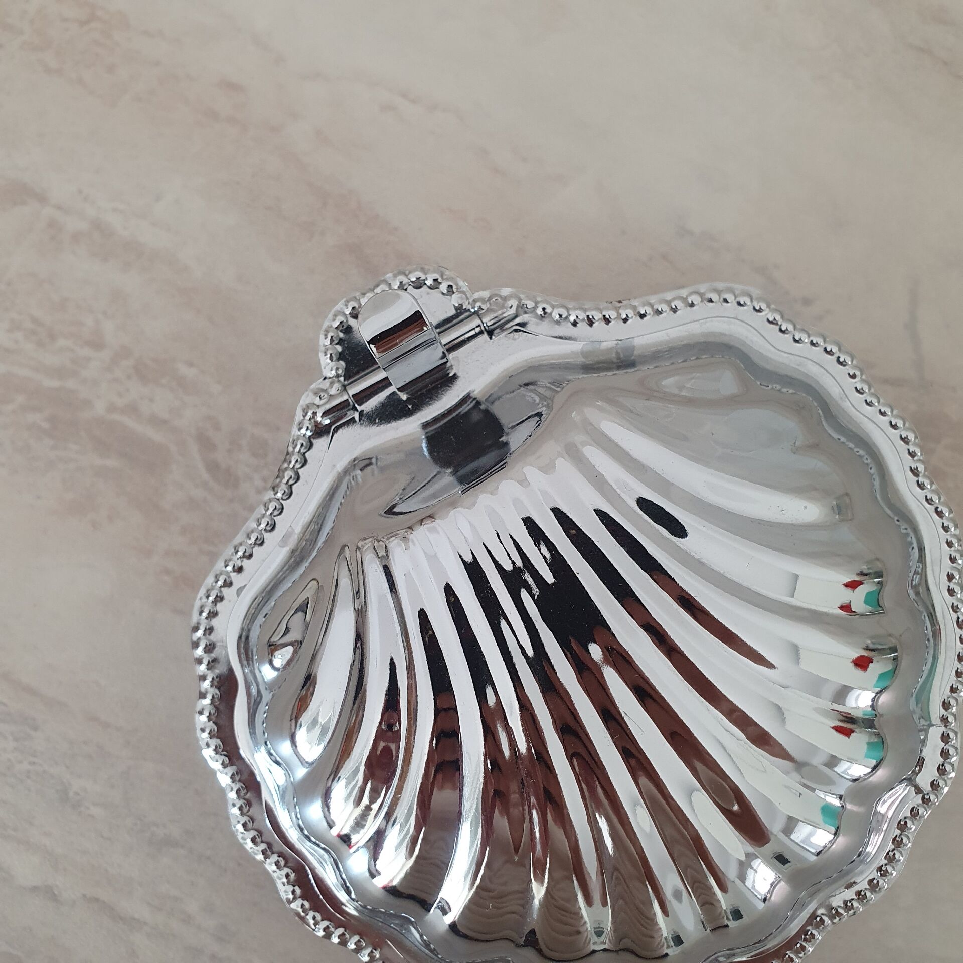 Shell-shaped butter dish in stainless steel and white glass bowl.