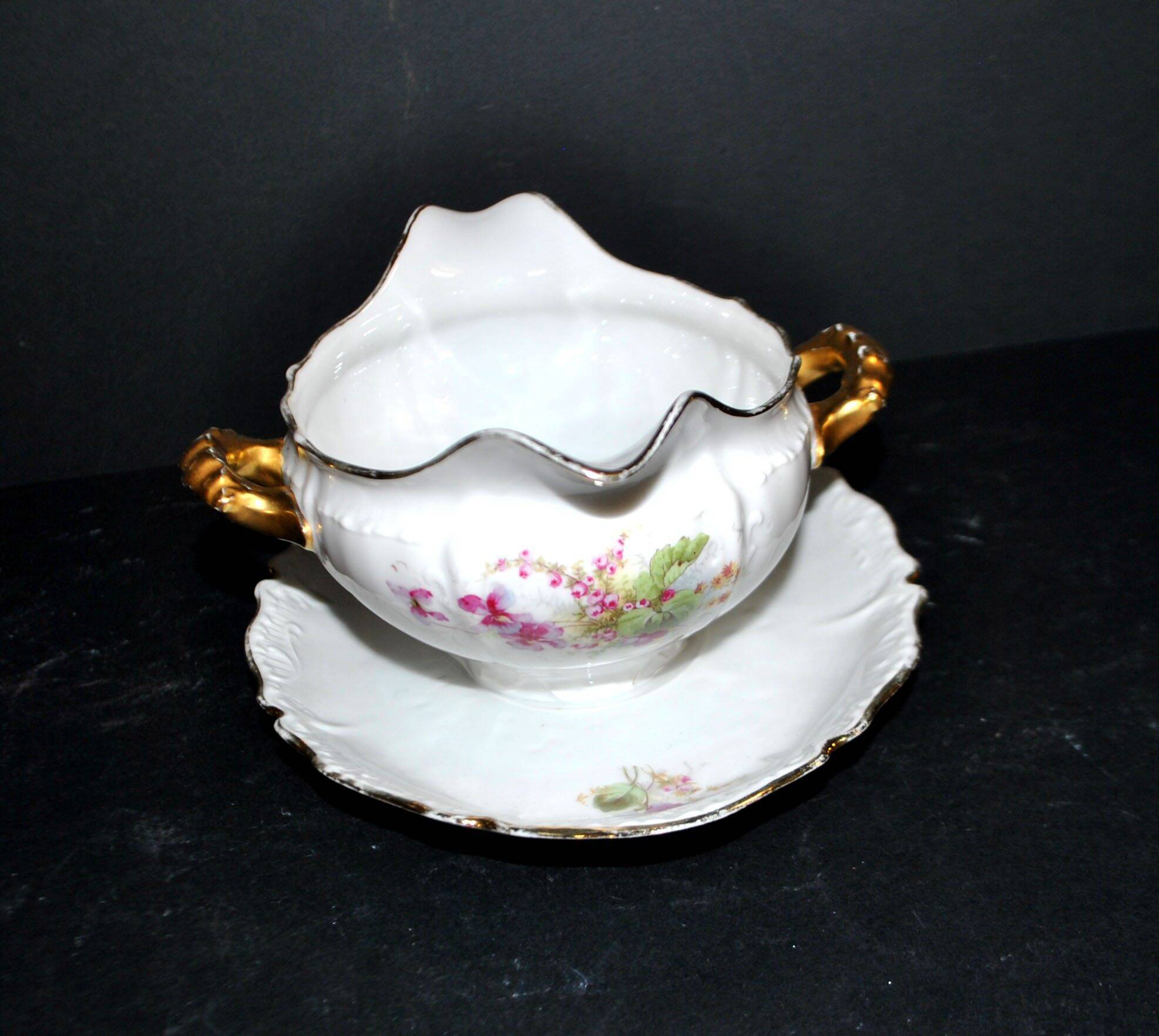 Vintage pouring sauce boat in floral porcelain with gilding.