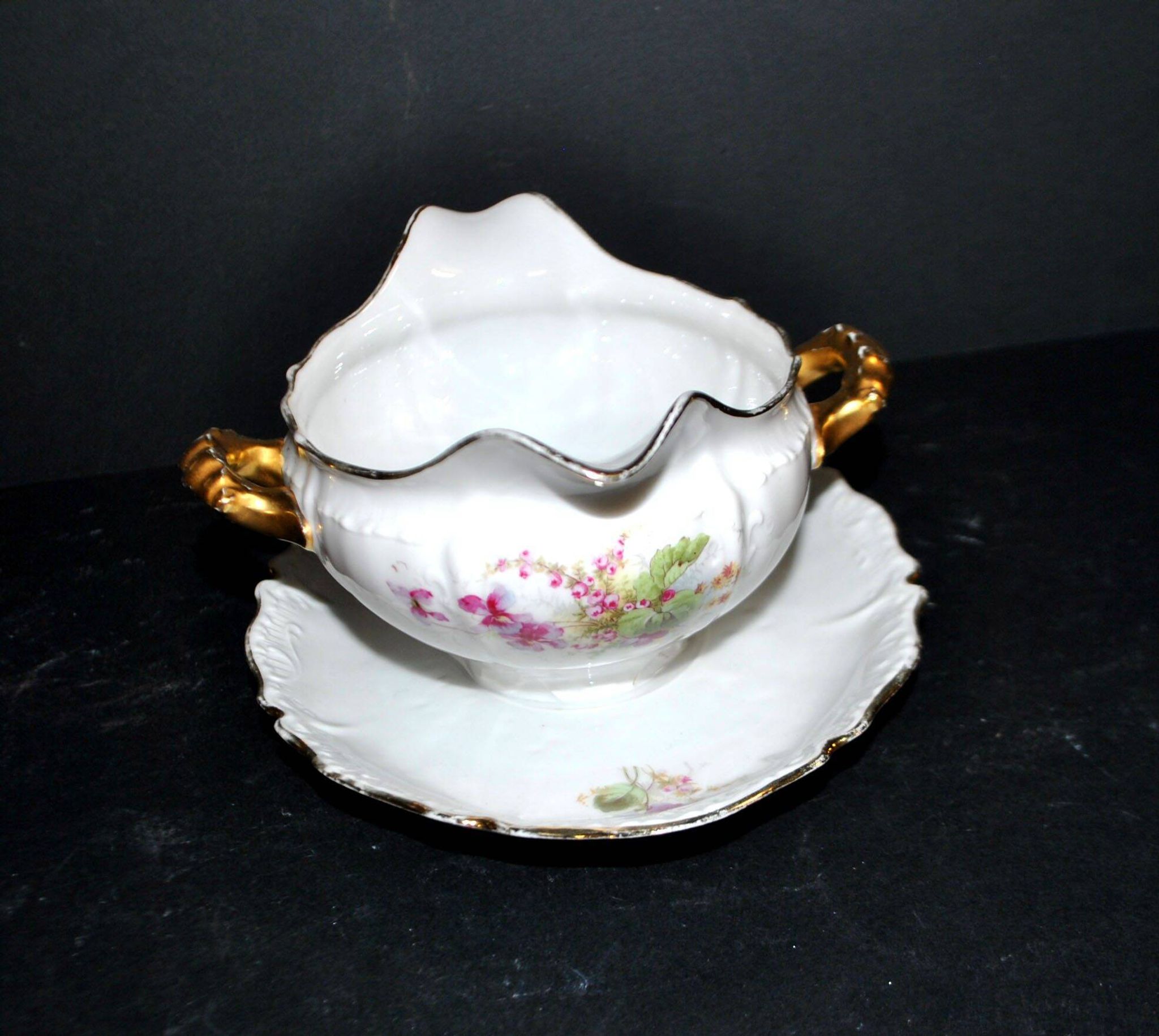 Vintage pouring sauce boat in floral porcelain with gilding.