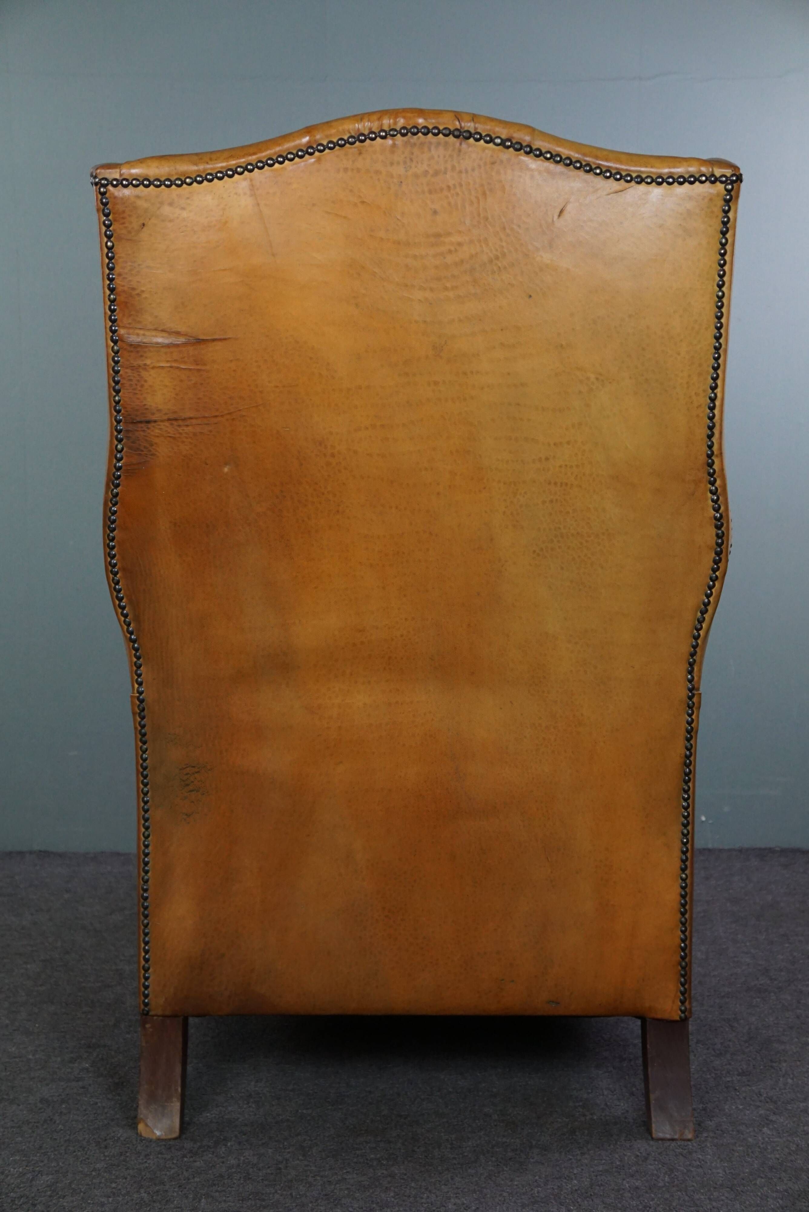 Old wingback armchair made of sheep leather in a correct condition
