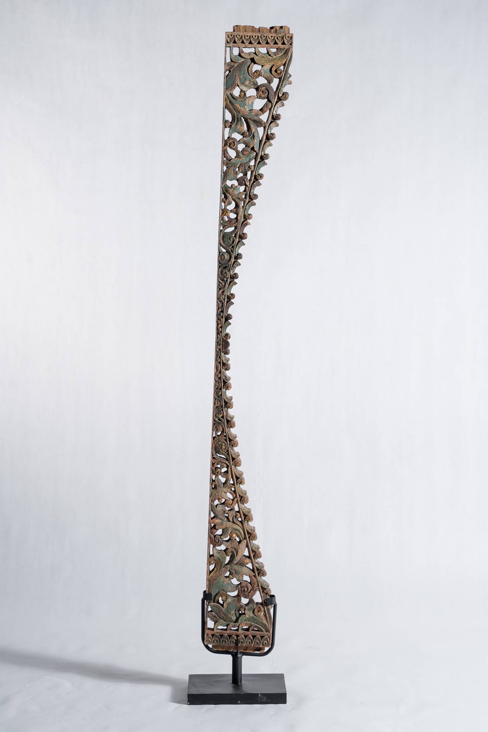 Indonesian construction element in carved wood with intertwined plant motifs mounted on a base (fri