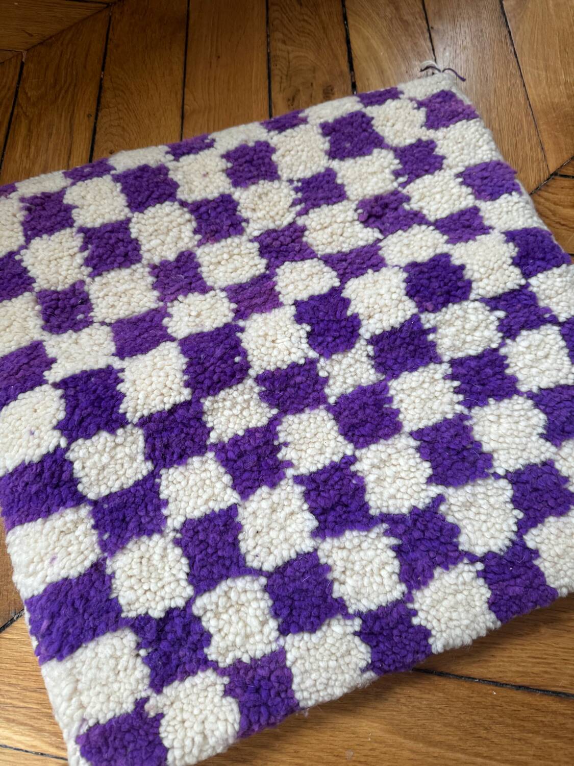 Square cushion cover with a checkered pattern.