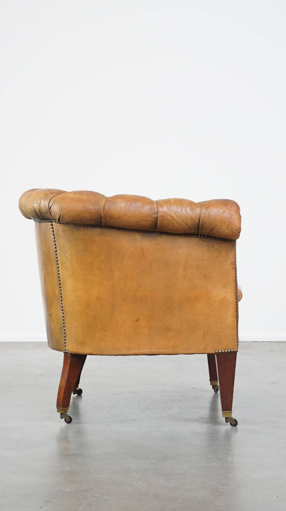 Antique, characteristic sheepskin chesterfield club chair on wheels