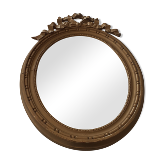 Old oval wooden mirror, surmounted by a knot