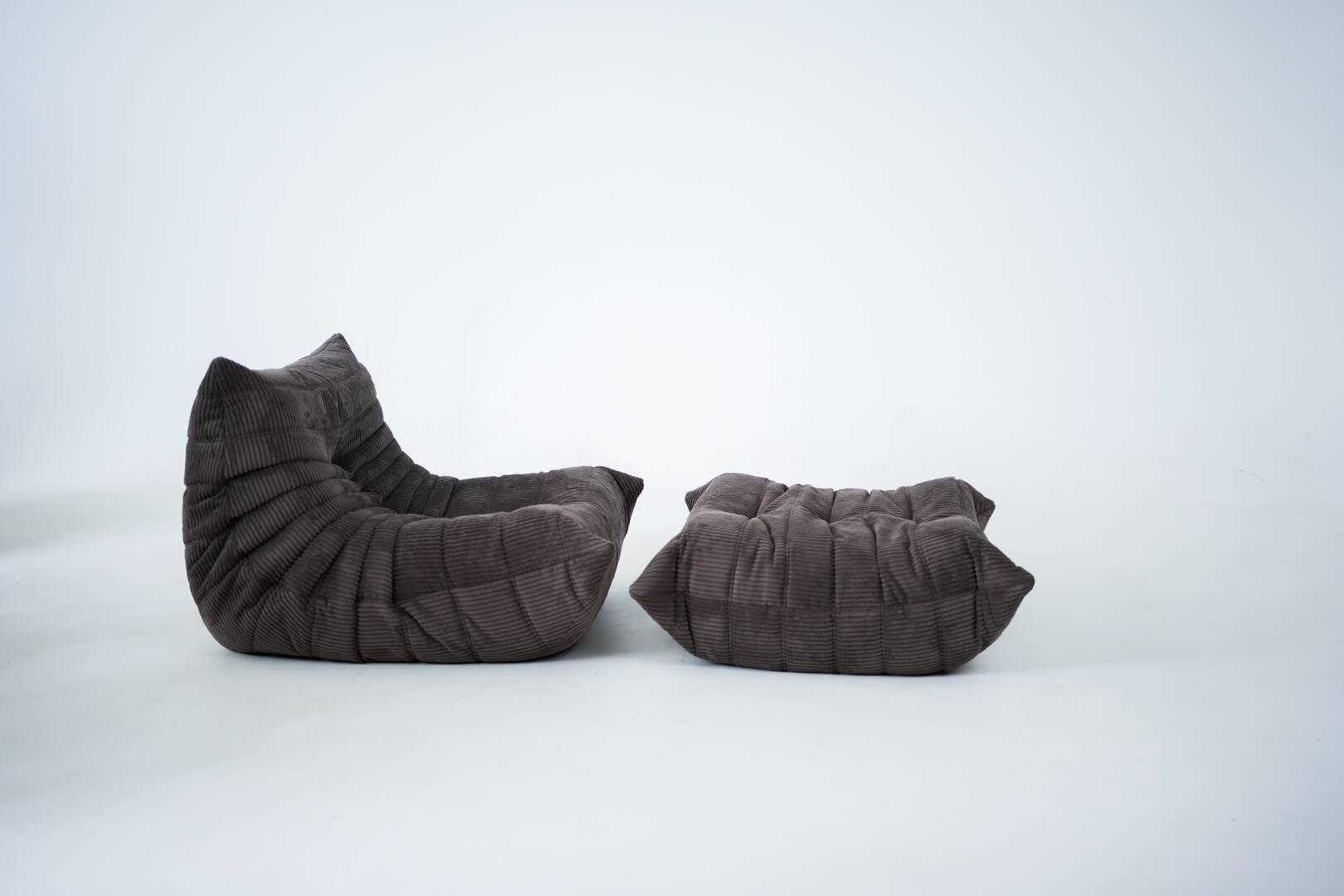 Ensemble de chaise et pouf Togo en velours côtelé marron.