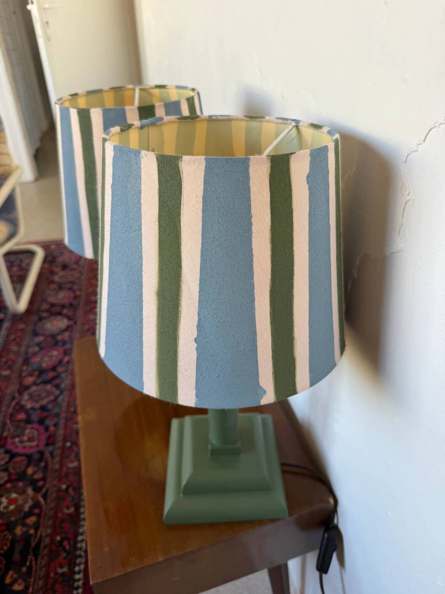 Pair of vintage wooden lamps with their striped beige, blue, and green shades.