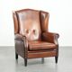 Sheepskin wingback armchair in a warm cognac colour with refined nailhead trim