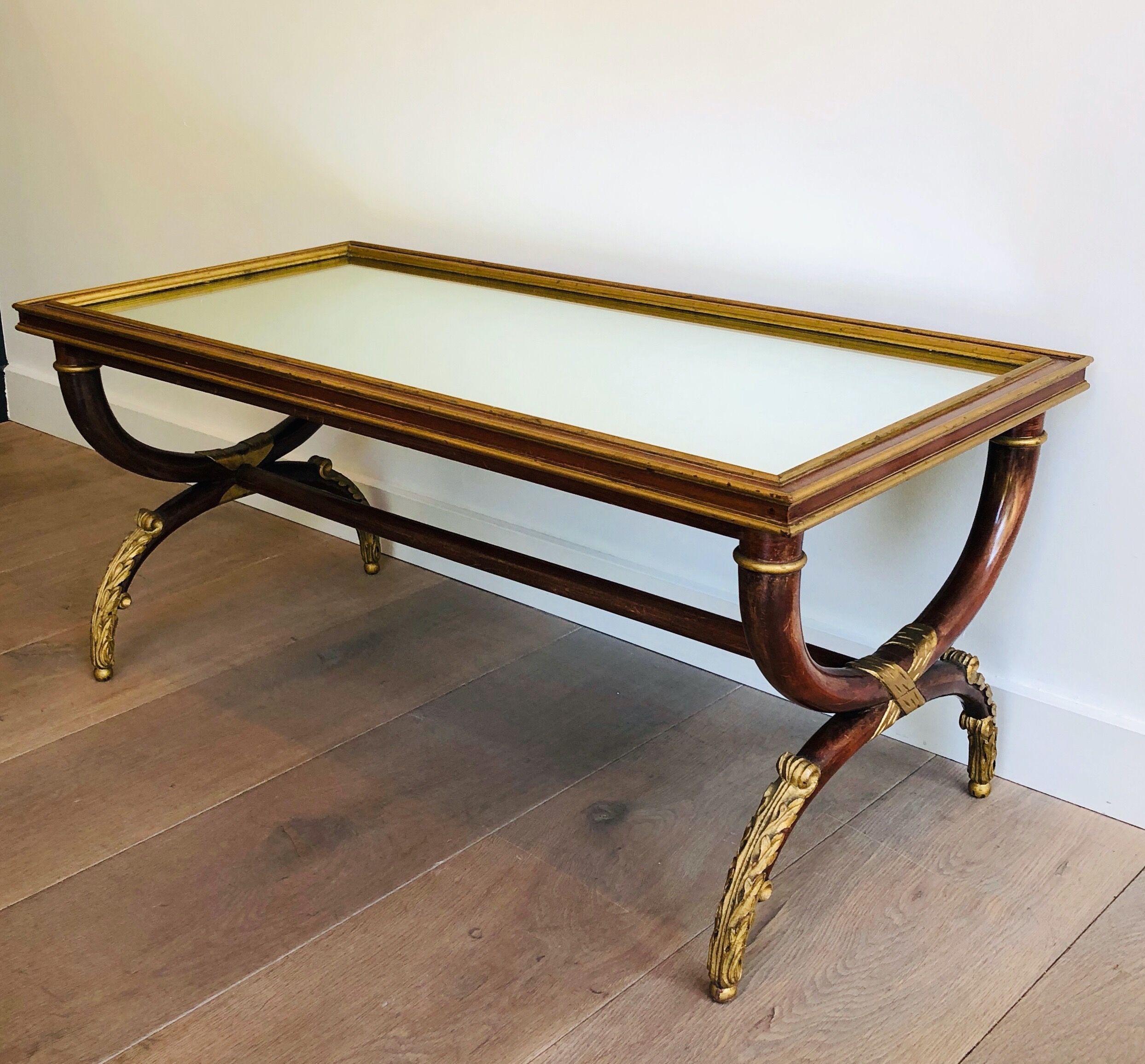Coffee table in patinated and gilded carved wood with mirror top