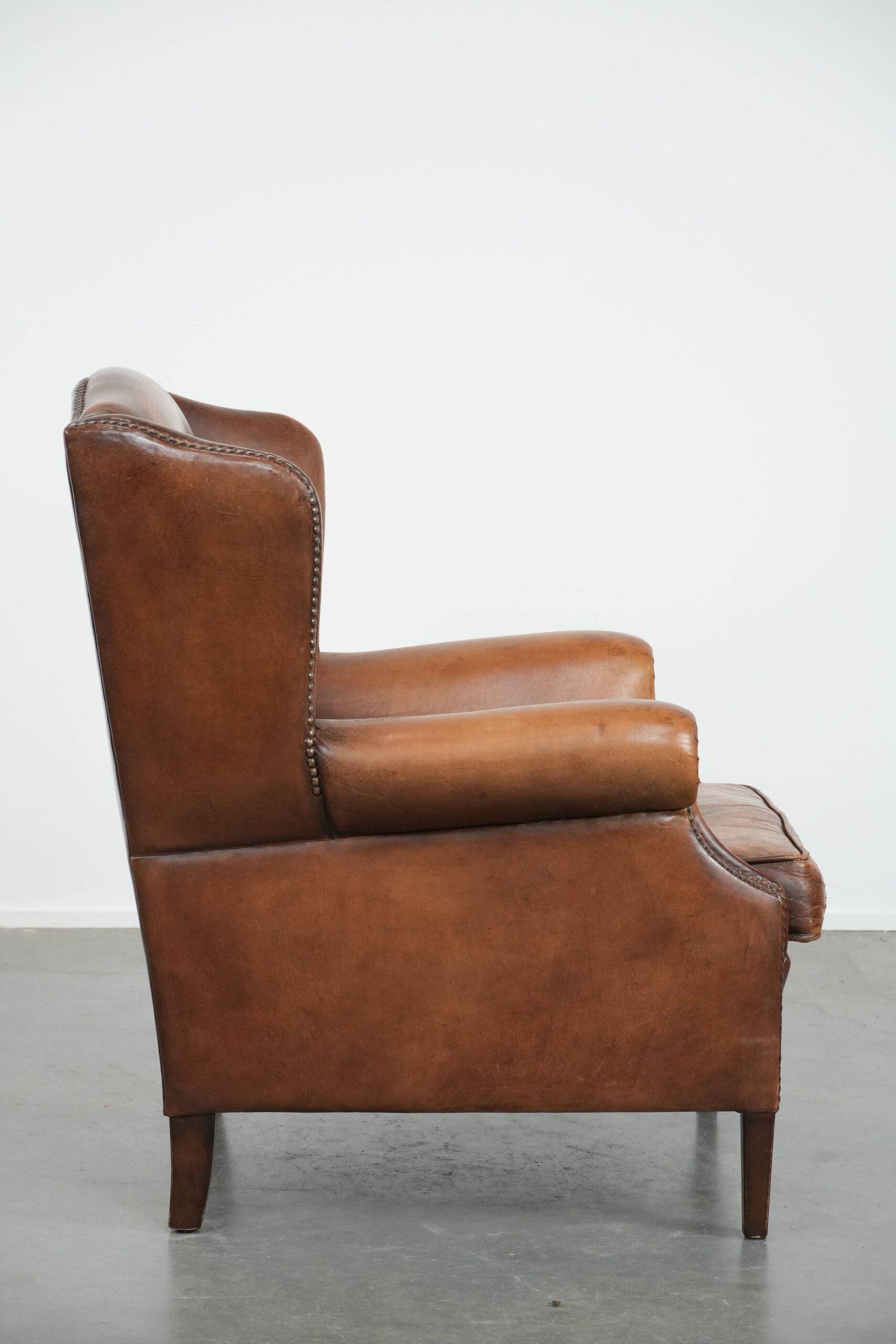 Fauteuil à oreilles en cuir de mouton charmant avec des couleurs chaudes.