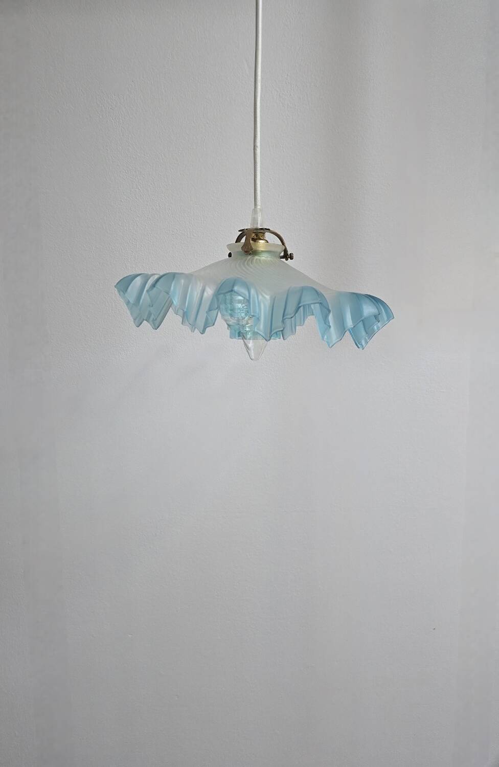 Suspension lampshade with scalloped edges in blue and its interior decoration.