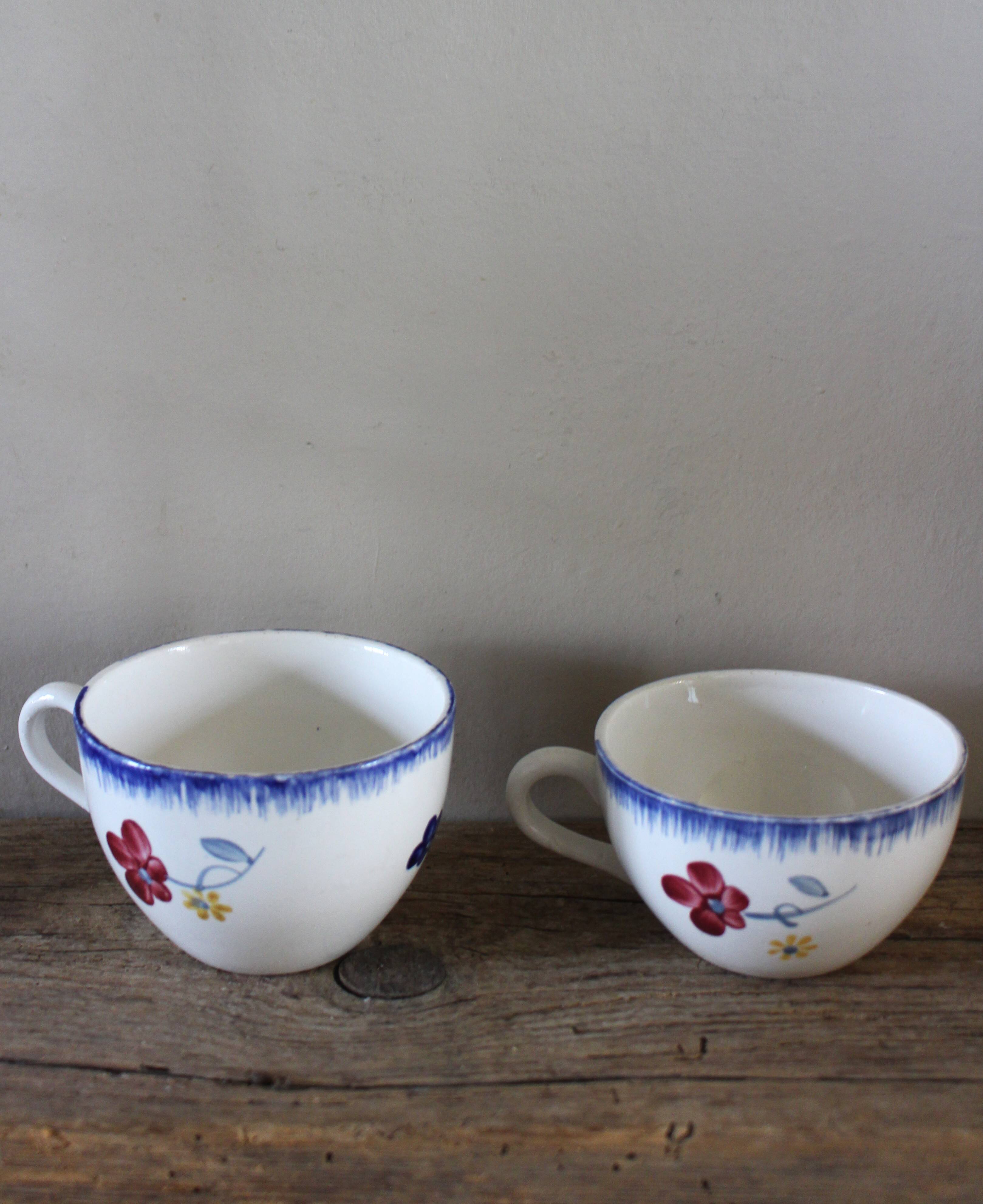 A set of two Digoin earthenware cups with blue, red, and yellow flowers.