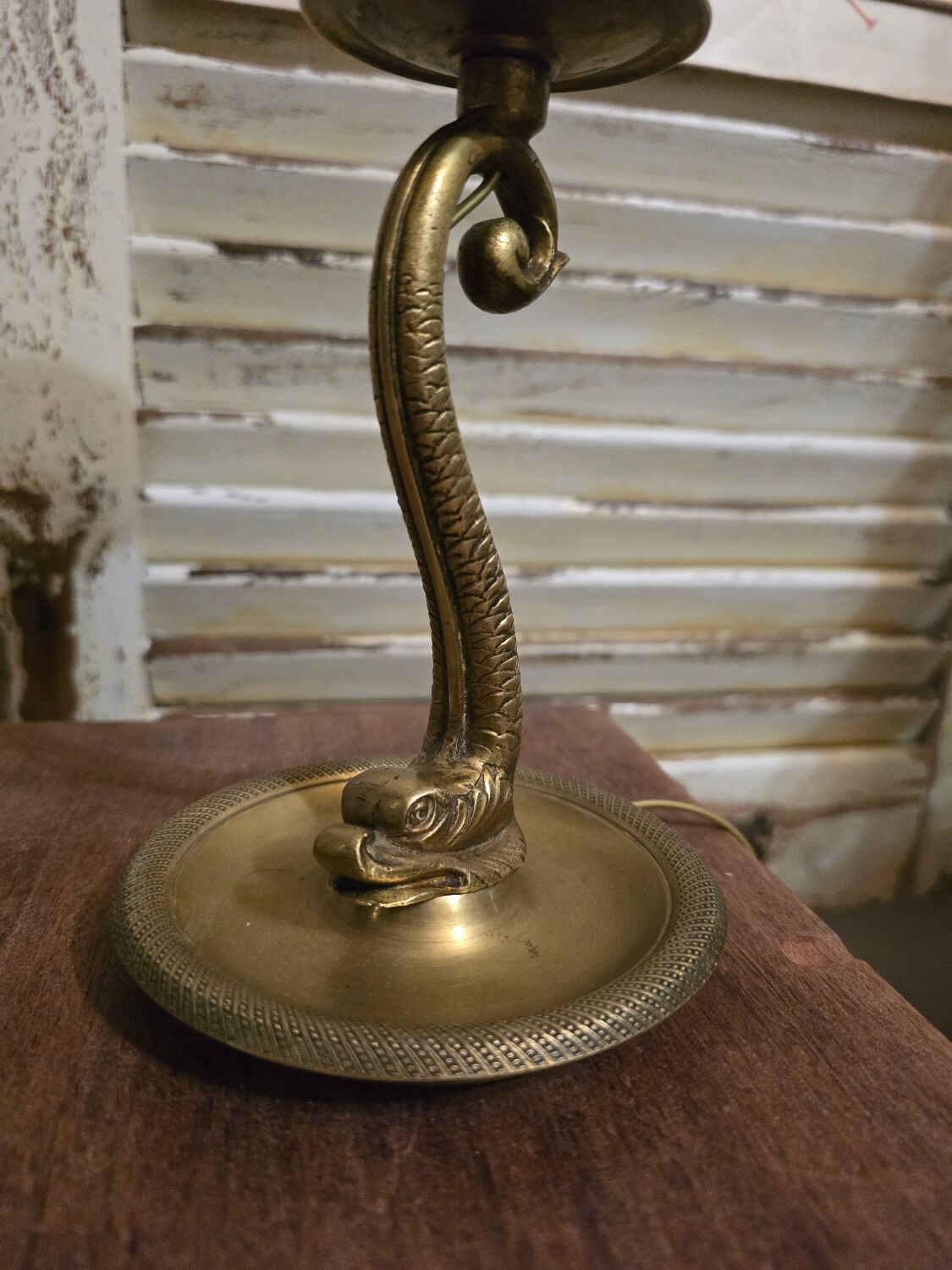 Small table lamp with a brass fish base and a tulip shade with green edges.