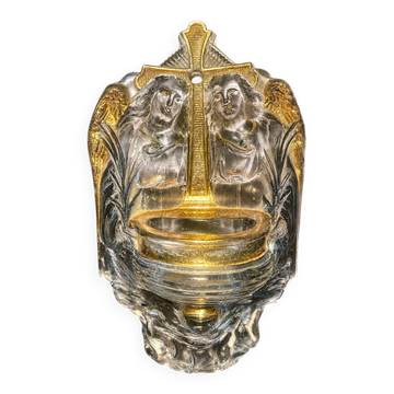 Old wall-mounted holy water font in moulded glass decorated with angels.