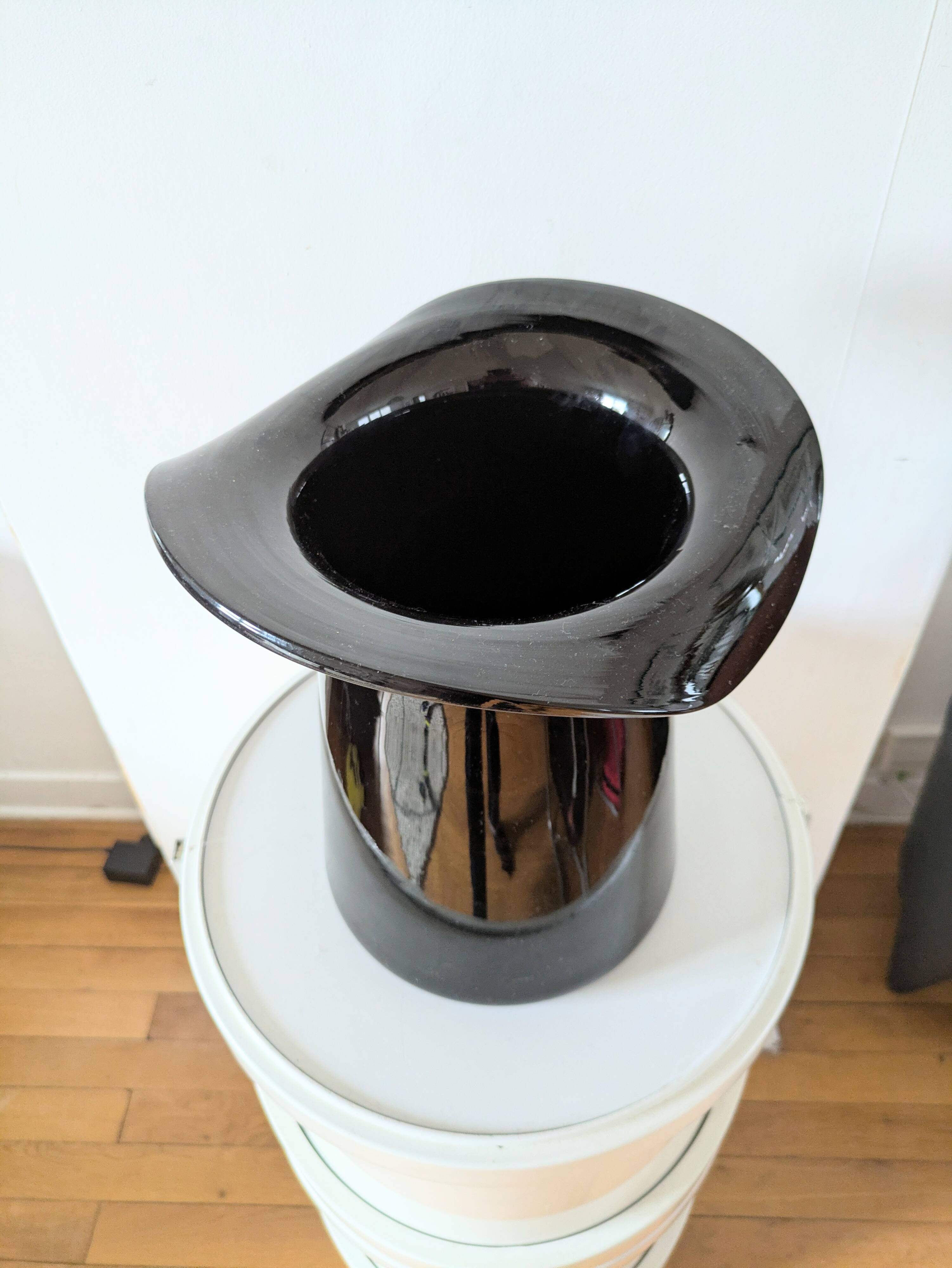 Large black glass vase topped with a 70s hat