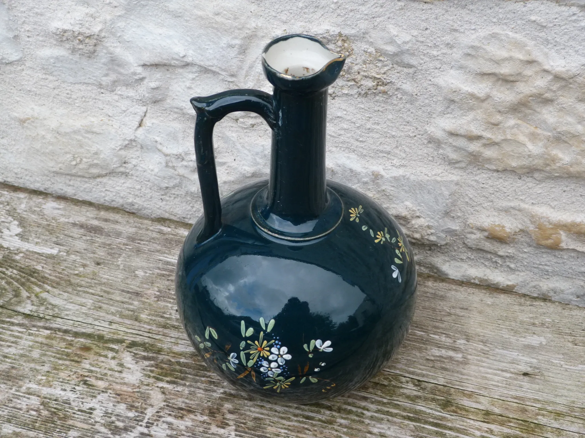Old ceramic jug with flowers or single-stem vase.