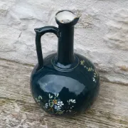Old ceramic jug with flowers or single-stem vase.