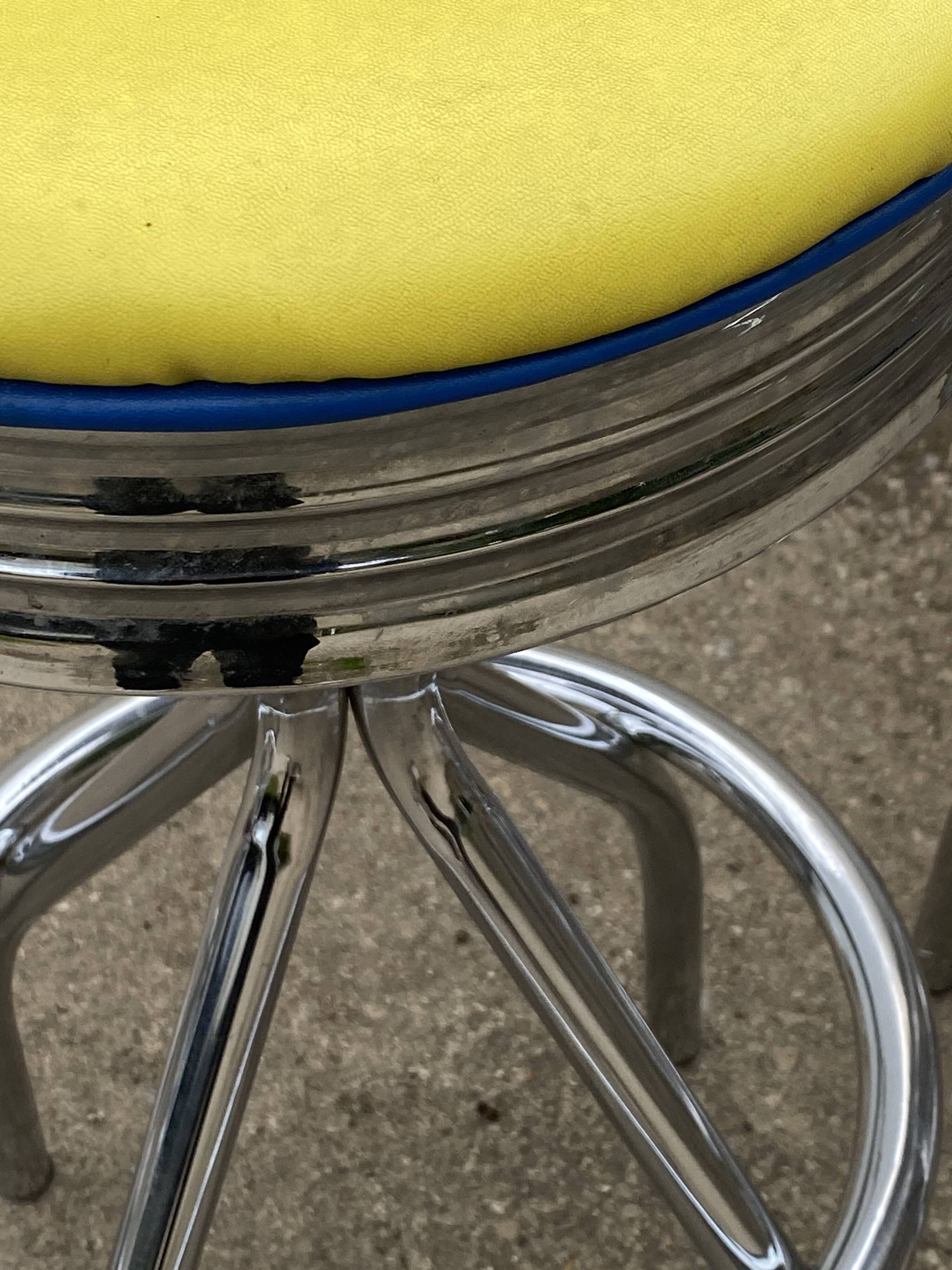 Set of 5 vintage swivel bar stools in blue, red, orange, and yellow.