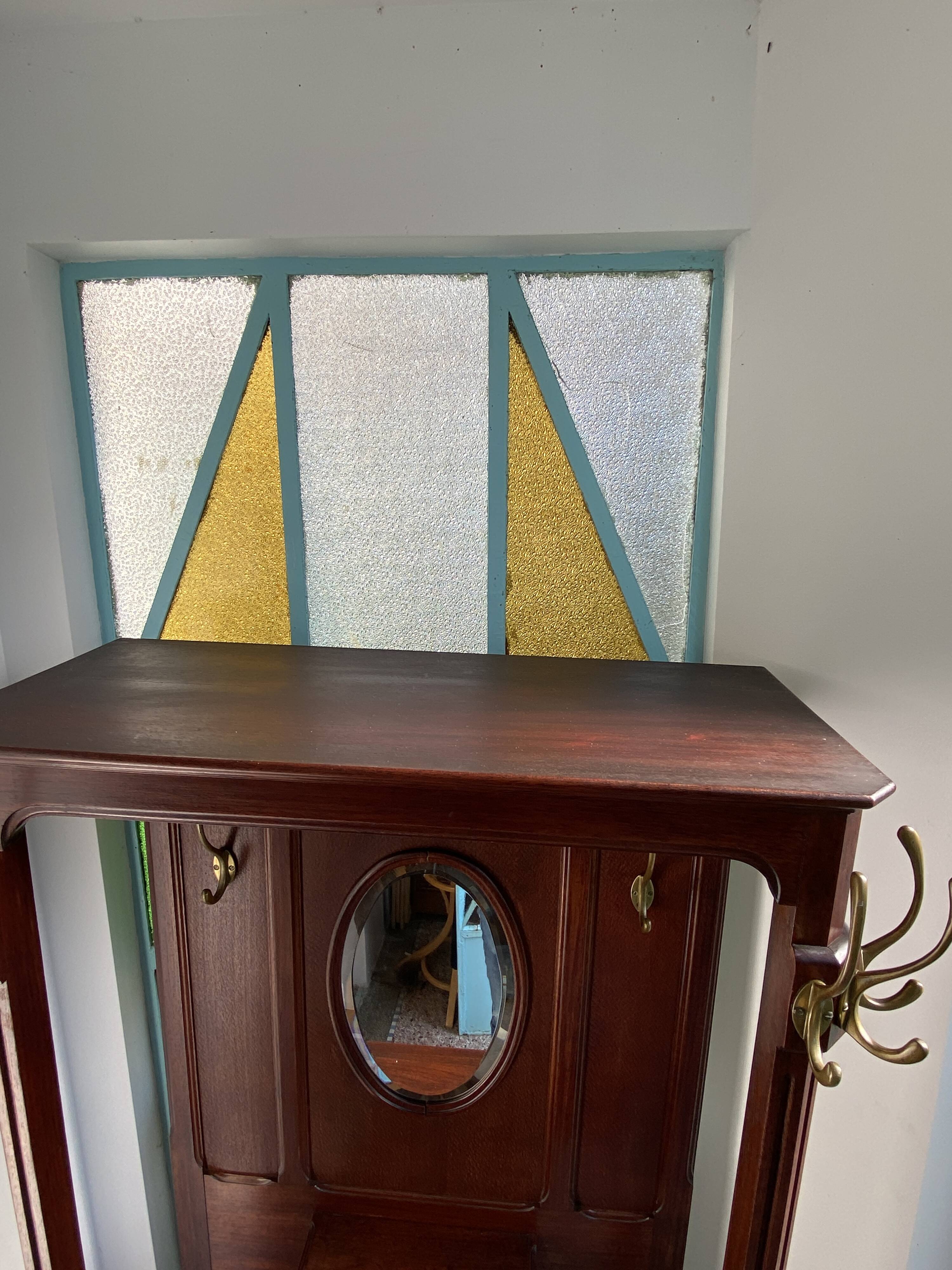 Antique wooden coat rack with mirror and shelf.