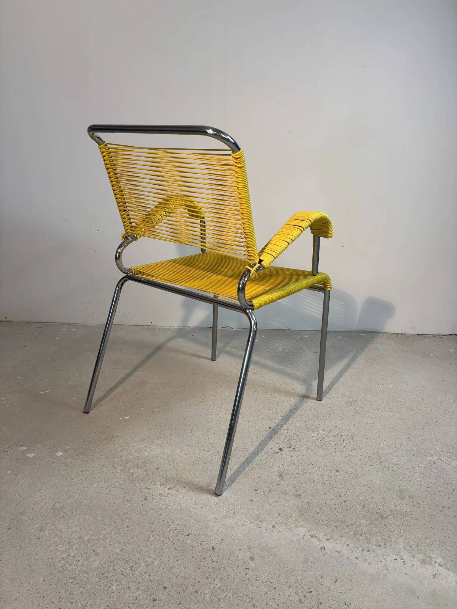 Yellow scoubidou armchair with a chrome tubular frame.