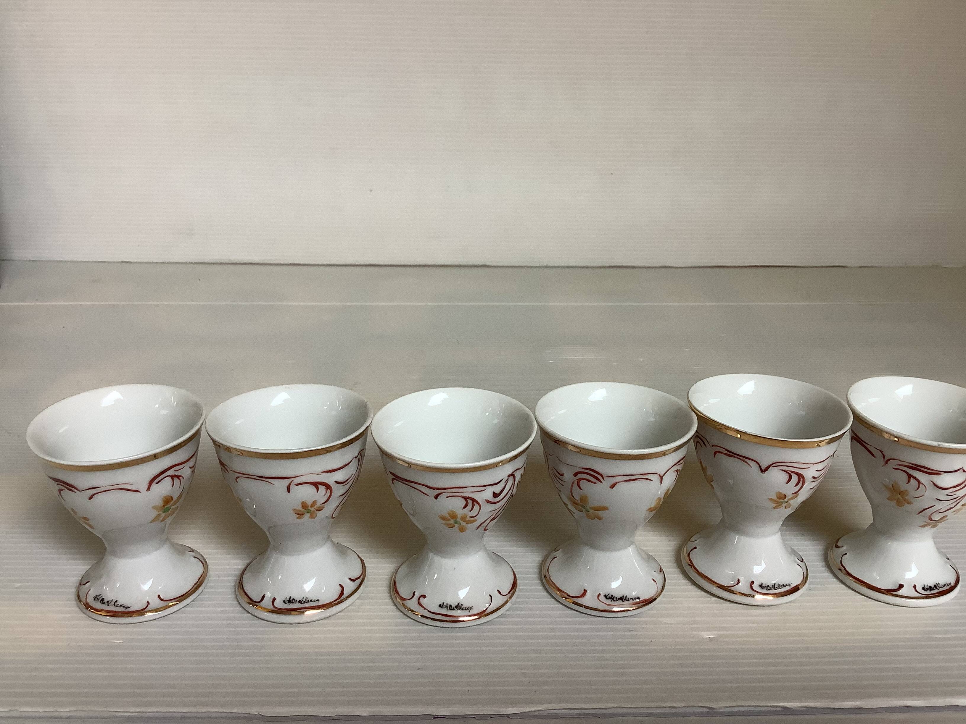 Six hand-decorated and signed egg cups