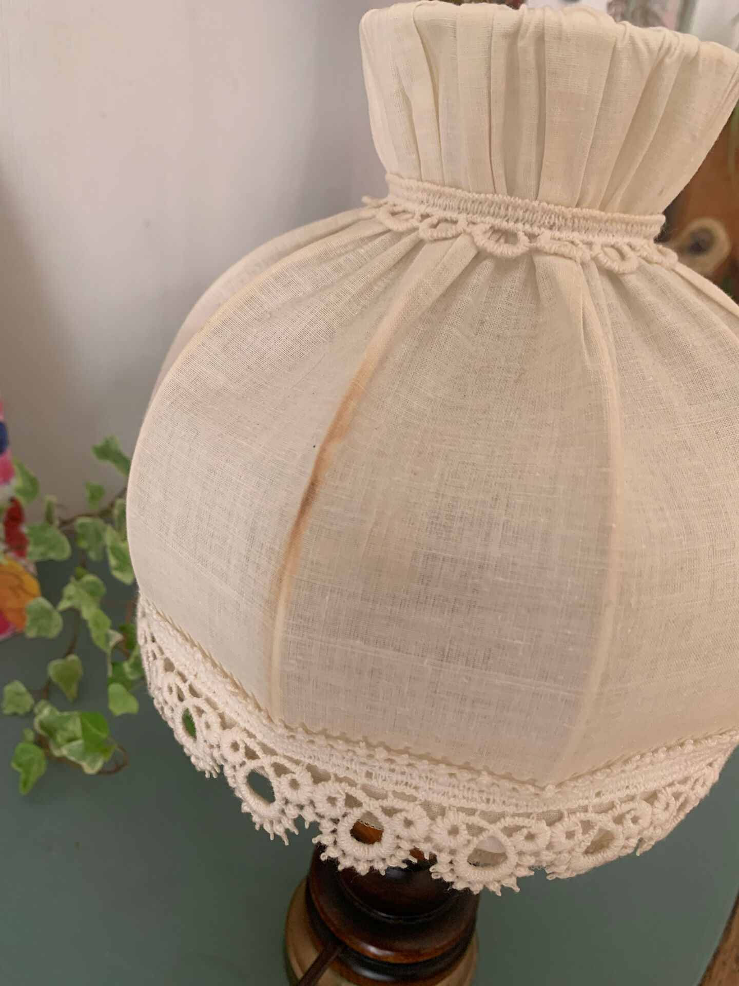 Small vintage wooden turned table lamp with a pleated shade.