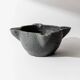 Vintage ceramic ashtray from the 1960s, black, hand-sculpted texture, organic shape.