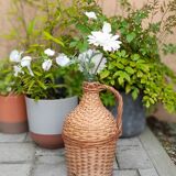 Old demijohn with handle covered with wicker