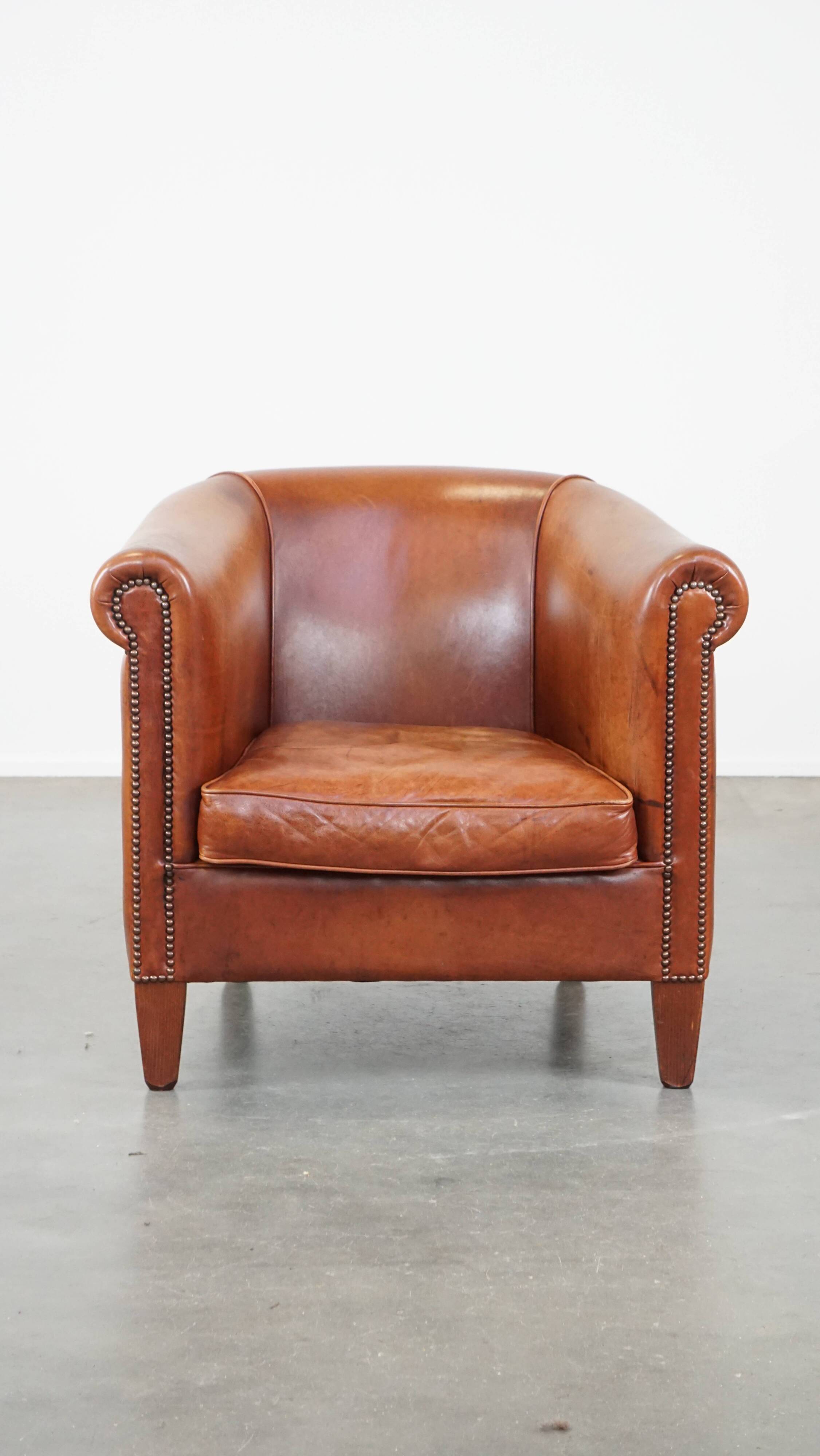 Cognac-colored cow leather club chair finished with decorative nails in English style