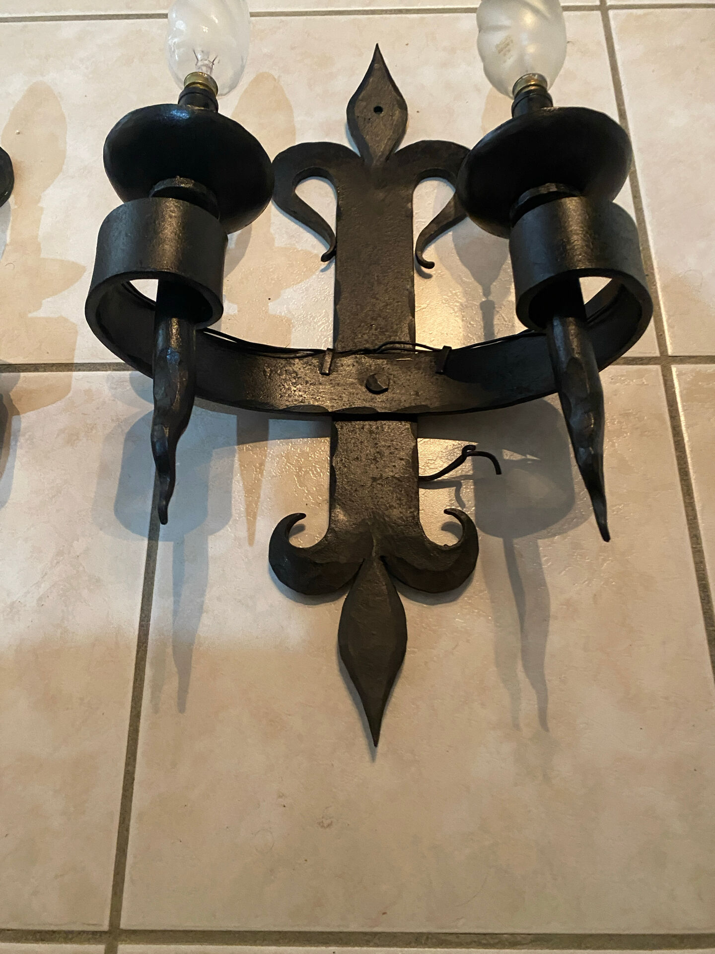 Pair of wrought iron wall lights in fleur-de-lis château style.