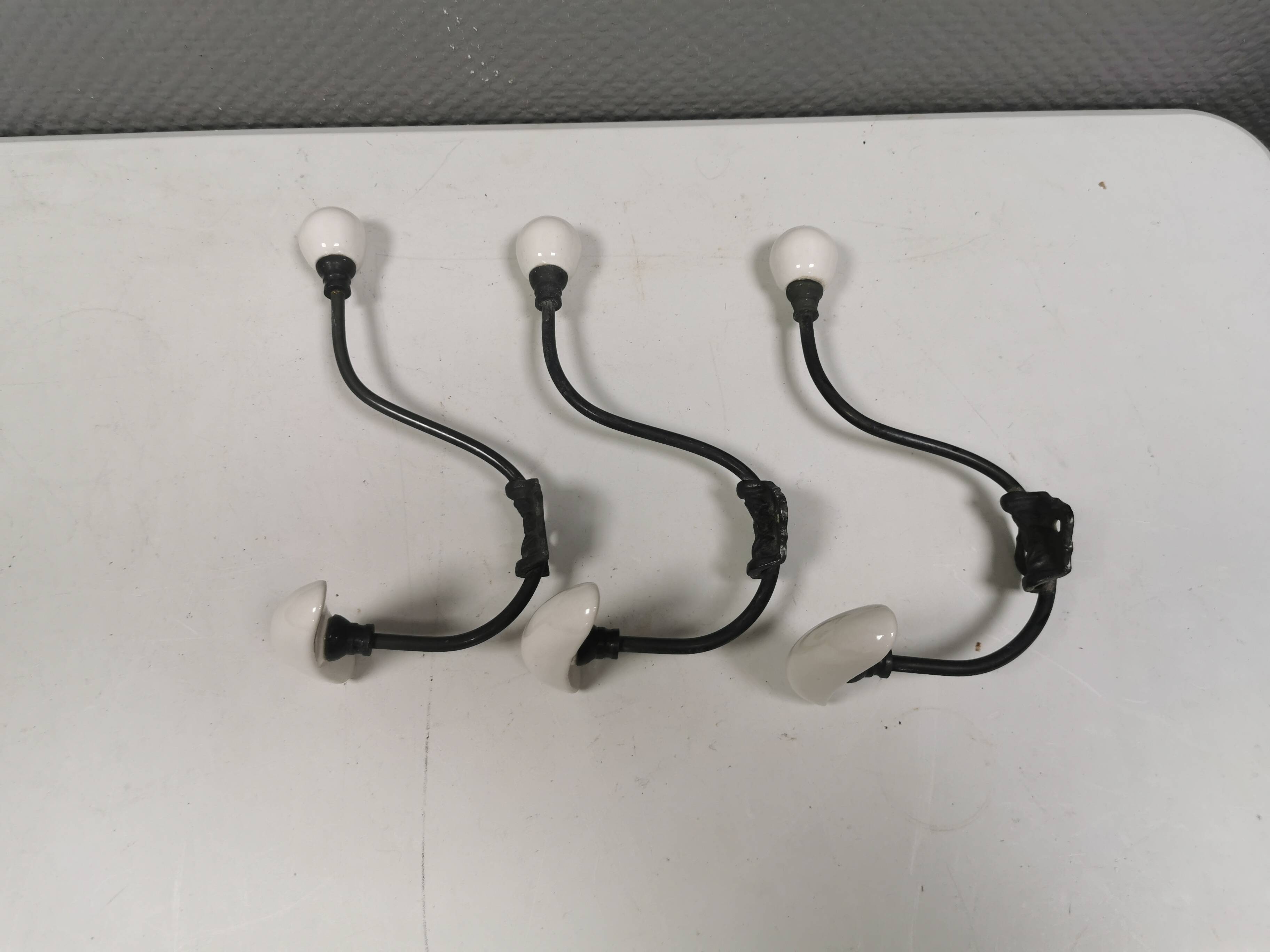 Coat hooks made of galvanized brass and raw white porcelain