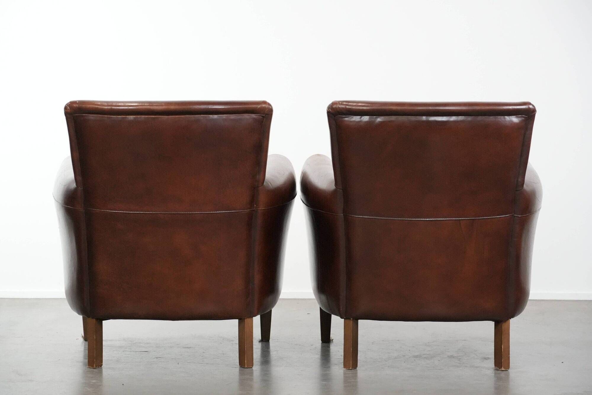 Ensemble de deux fauteuils en cuir de mouton vintage au caractère marqué.