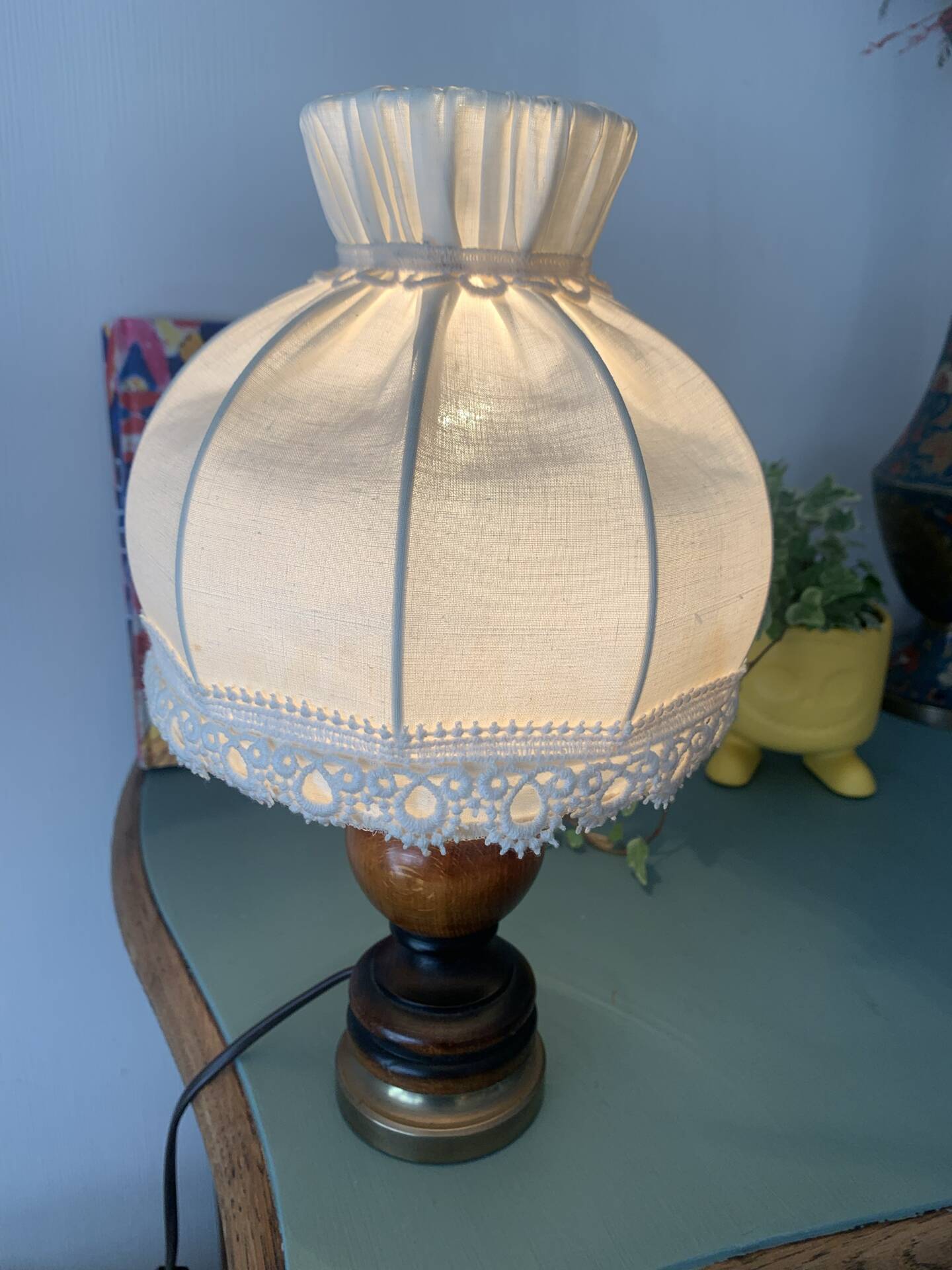 Small vintage wooden turned table lamp with a pleated shade.