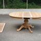 Round dining table with a central pedestal, extendable, stripped in solid walnut with 2 extensions.
