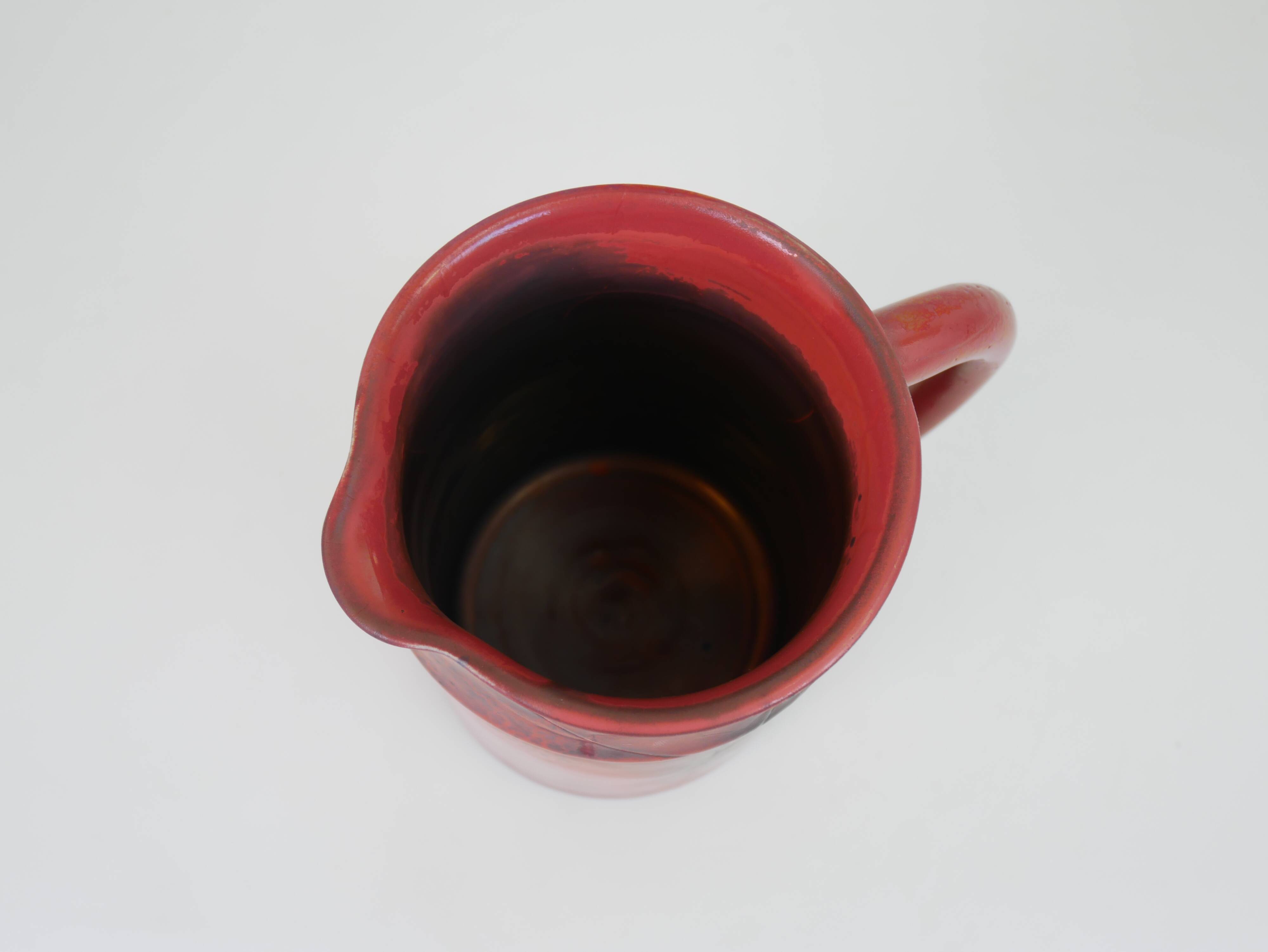 Red glazed ceramic jug with relief