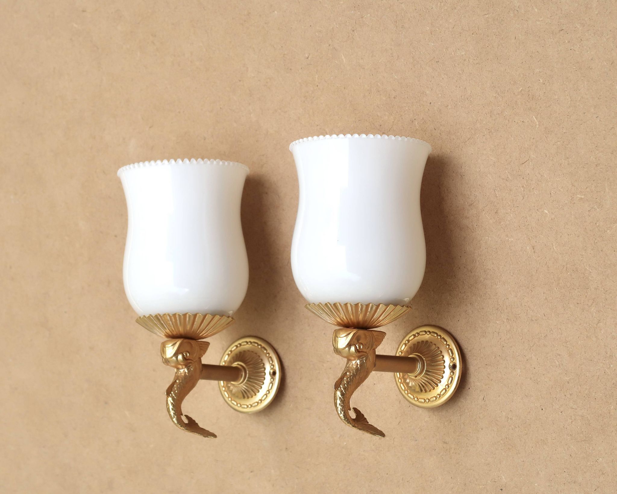 Pair of gold metal and opaque glass wall lights adorned with fish from the 1950s.