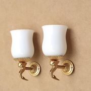 Pair of gold metal and opaque glass wall lights adorned with fish from the 1950s.