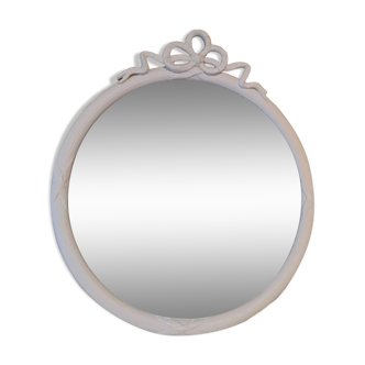 Round mirror in carved wood with at the top a ribbon forming a knot in cream color