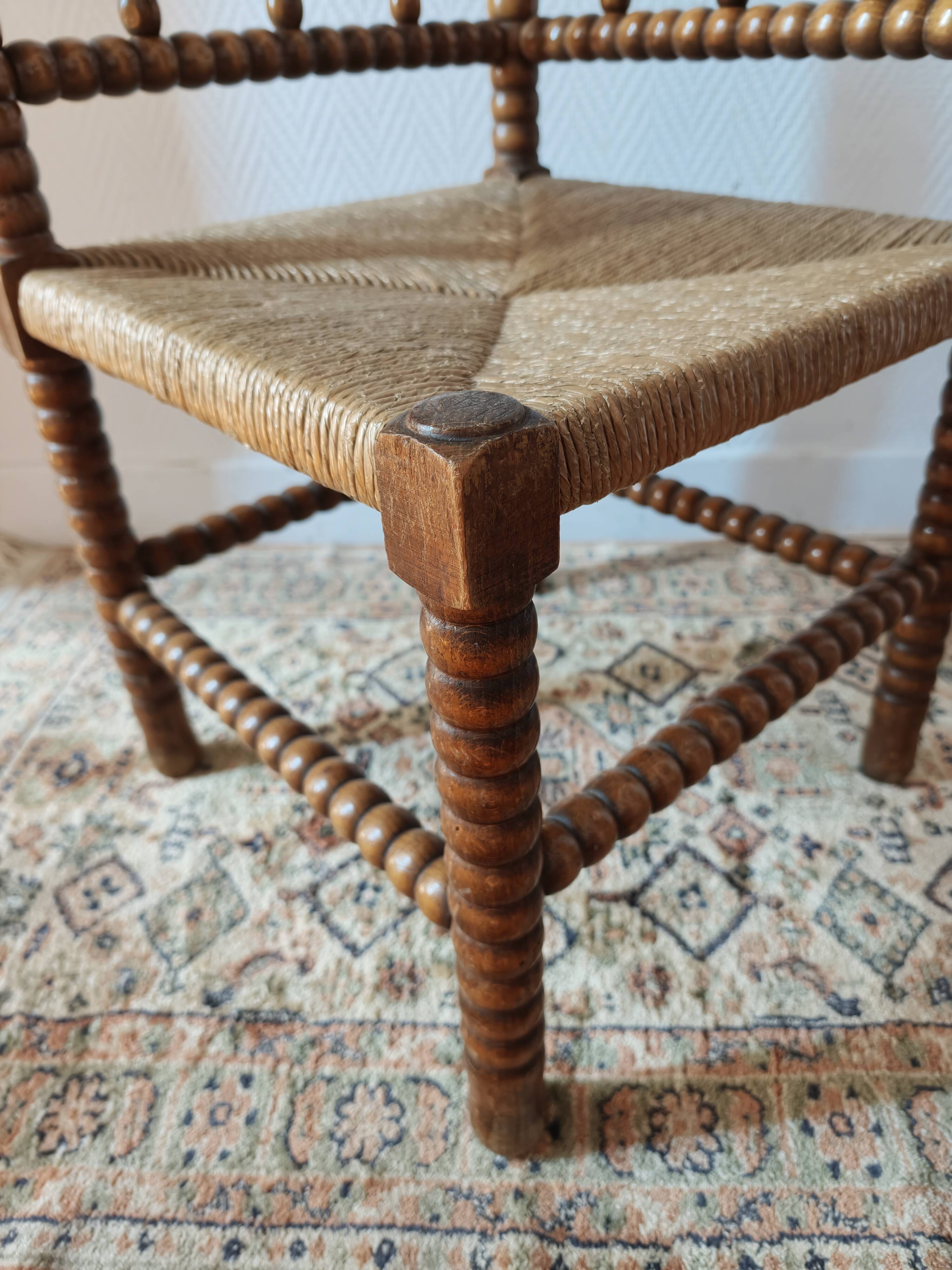 Antique corner chair by the fire with turned wood and straw seat.
