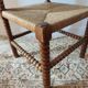 Antique corner chair by the fire with turned wood and straw seat.