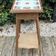 Antique wooden plant stand with ceramic tiles.