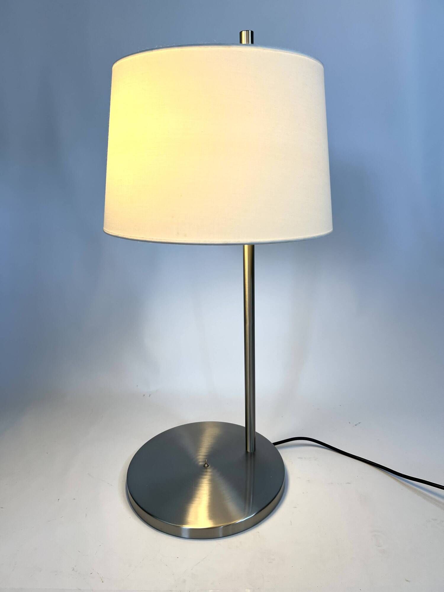 Large brushed metal table lamp with an ecru shade.
