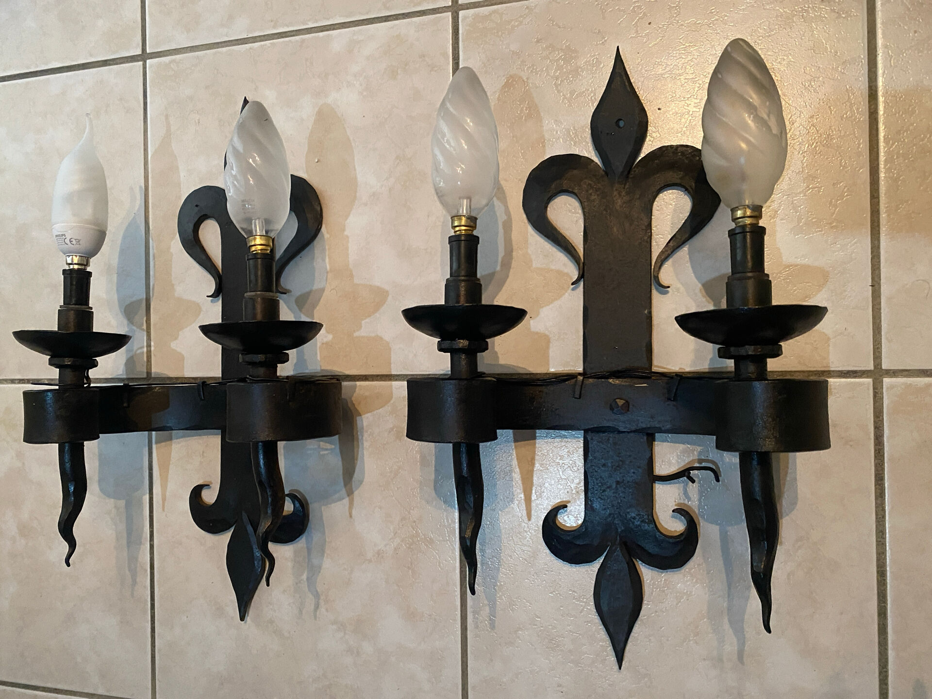 Pair of wrought iron wall lights in fleur-de-lis château style.