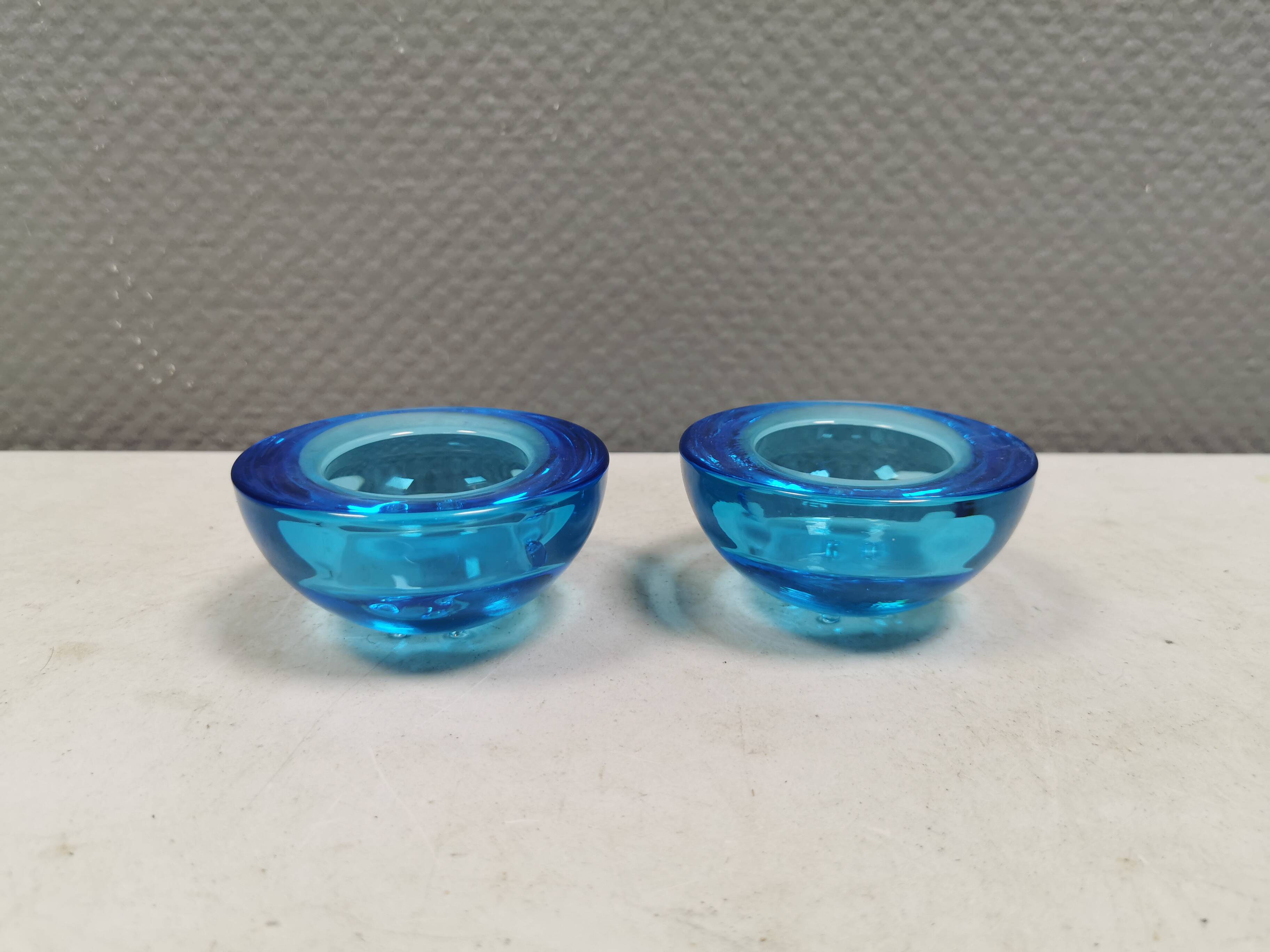 A set of iitalla candle holders in blue transparent glass.