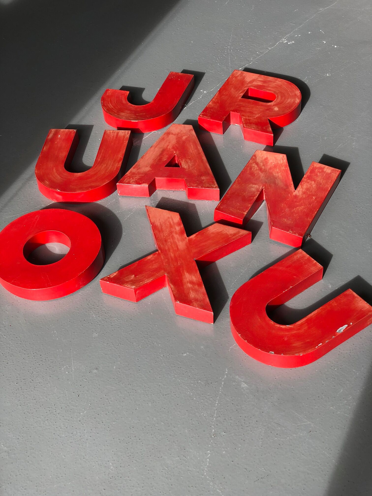Lettres d'enseigne en zinc rouge formant le mot JOURNAUX