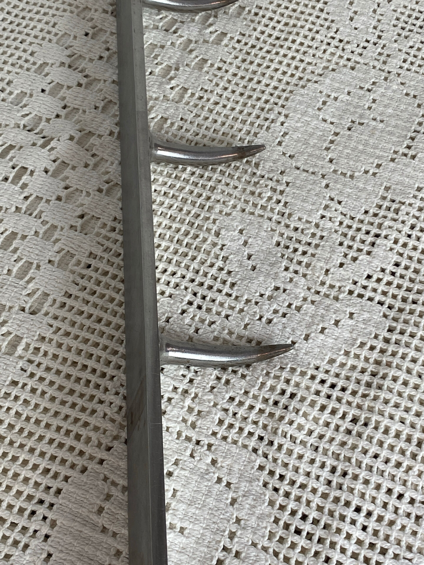 Stainless steel butcher's hook, known as a "wolf tooth bar."