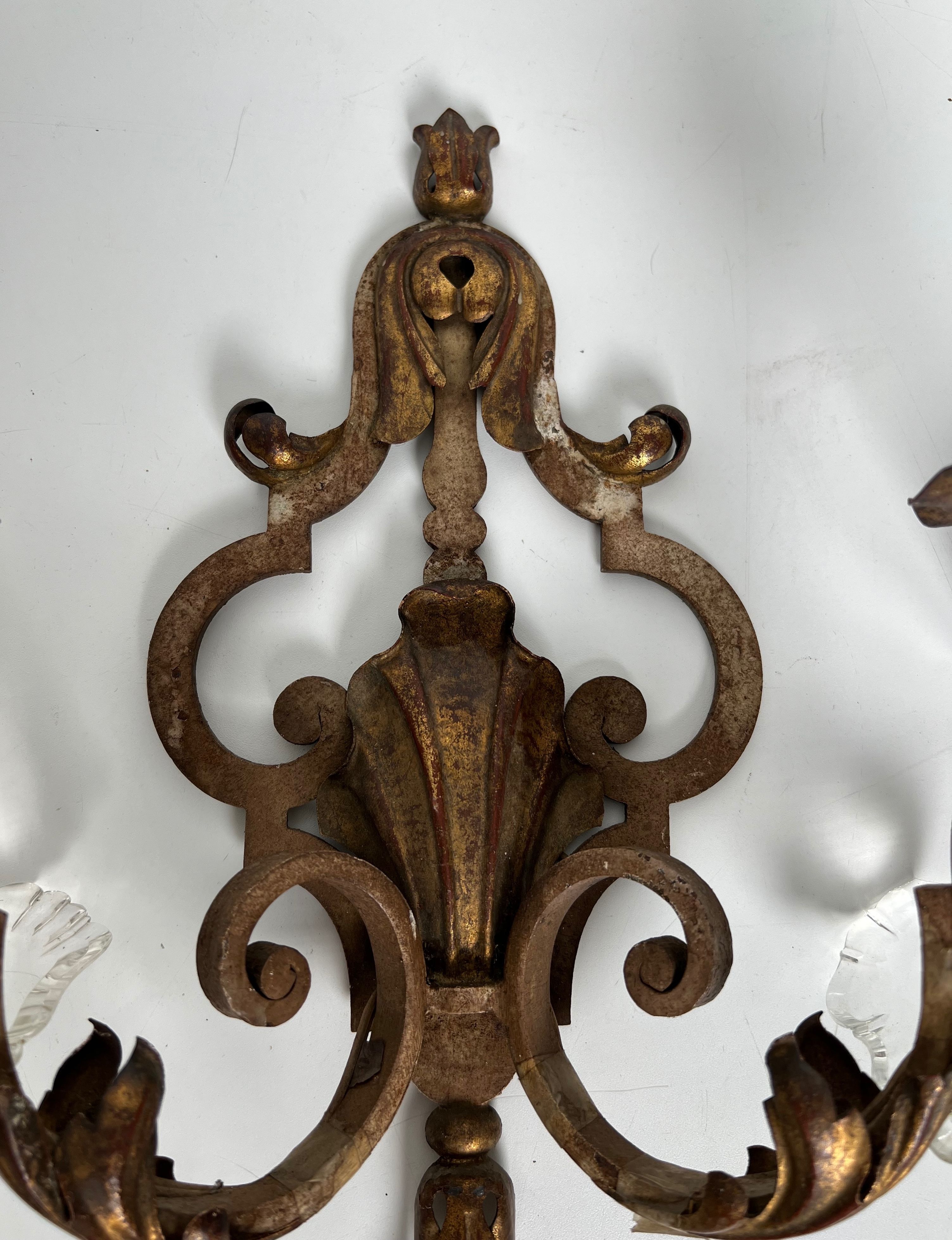 Pair of patinated wrought iron wall sconces with golden acanthus leaves and crystals.