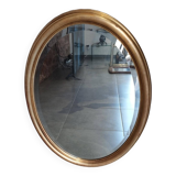 Large and elegant oval gilded mirror with its beveled glass