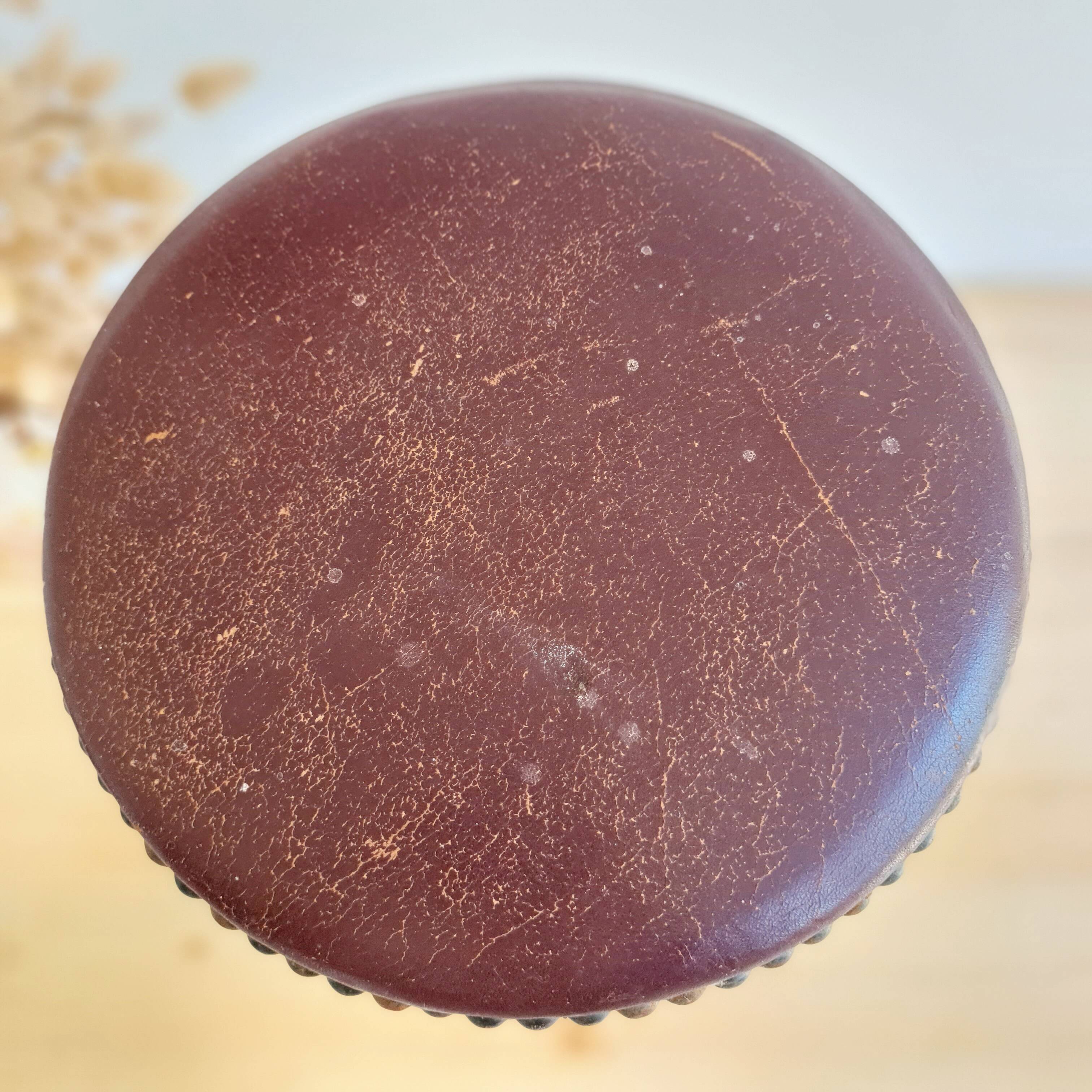Antique tripod stool with turned wooden legs and leather seat.