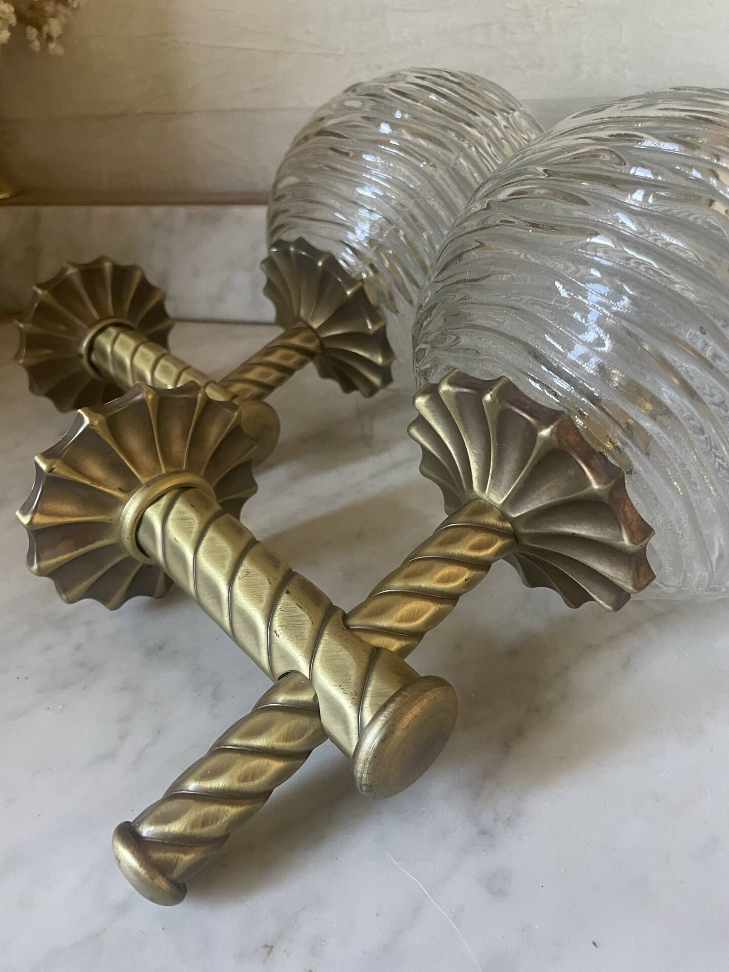 Pair of neoclassical wall sconces in twisted brass and ribbed glass.